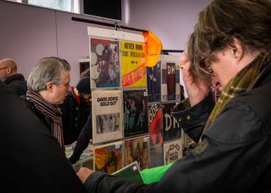 Collectible albums on display as men browse vinyl records at an enthusiast's Record Fair in Totnes, Devon, UK. clipart