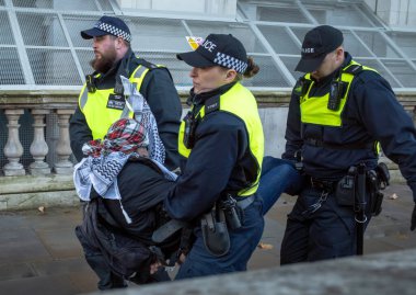 Londra / İngiltere - 9 Aralık 2023: İsrail 'in Gazze' deki saldırılarına karşı düzenlenen gösteride yüzünü kapatmayı reddettiği için tutuklanan Filistinli bir protestocu, polis tarafından kaçırıldı.