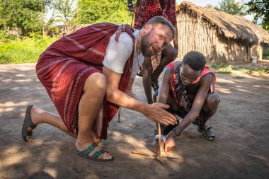Bir Masai savaşçısı Tanzanya 'nın Mikumi kasabasında çubukları birbirine sürttükten sonra ateşle başlar..