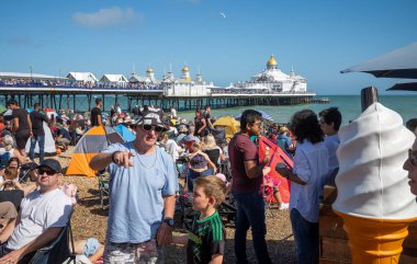 Uluslararası bir uçuş gösterisi olan Eastbourne Havaalanı 'na katılan insanlar Eastbourne İskelesi' nin yanındaki plajı dolduruyorlar.
