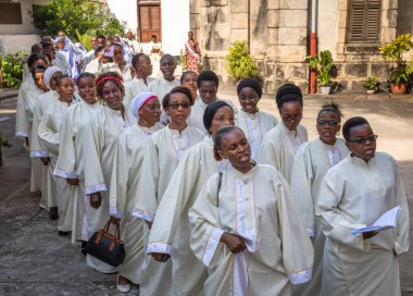 Beyazlar içindeki koro, Stone Town, Zanzibar, Tanzanya 'daki Katolik Pazar Ayini için St. Joseph Katedrali' ne girerken şarkı söylüyor..