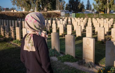 A foreign woman tourist views graves of British soldiers killed in North African Campaign Feb 1943, Enfidaville War Cemetery, Enfidha, Tunisia. clipart