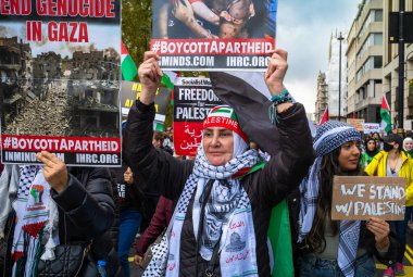 Londra / İngiltere - 21 Ekim 2023: Müslüman kadınlar, diğer Filistinli protestocularla birlikte Londra 'nın merkezinde İsrail' in Gazze 'ye düzenlediği saldırılara karşı düzenlenen büyük bir gösteride pankart tutuyorlar..
