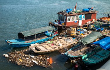 Cua Ong, Quang Ninh, Vietnam 'da Ha Long Körfezi' nin kıyısında çöplerle çevrili küçük ahşap botlar..