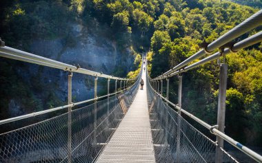 Fransız Alpleri, Mayres-Savel, Isere, Fransa 'da Monteynard Gölü üzerinden Passerelle du Drac Köprüsü' nü (Drac Footbridge) geçen insanlar...