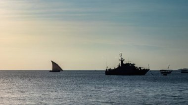 Geleneksel bir dhow yelkenlisi, Tanzanya 'nın Zanzibar kentindeki Stone Town' da bir Tanzanya donanma devriye teknesine yaklaşır.