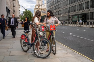 Londra / İngiltere - 11 Temmuz 2024: Londra 'nın merkezinde Westminster Katedrali yakınlarında Santander e-motorlu iki kadın.