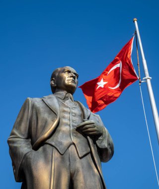 Çağdaş Türkiye 'nin kurucusu Mustafa Kamal Atatürk' ün büyük bronz heykeli, Türkiye 'nin Antalya ilindeki Side Old Town' da bir meydanda Türk bayrağını dalgalandıran bir bayrak direğinin yanında duruyor (Türkiye))