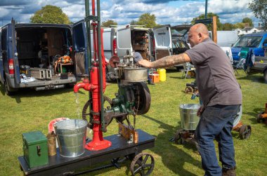 Erkek bir klasik motor meraklısı, makinesini Wisborough Green, West Sussex, İngiltere 'de bir köy şenliğinde ayarlıyor..