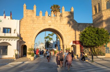 Turistler Tunus 'taki Port El Kantaoui limanının giriş kapısının yanında yürüyorlar..