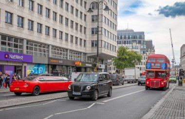 Londra / İngiltere - 11 Temmuz 2024: Geleneksel kırmızı bir Routemaster otobüsü, siyah bir elektrik Londra taksisi ve Victoria Caddesi, Londra 'da kırmızı bir limuzin.