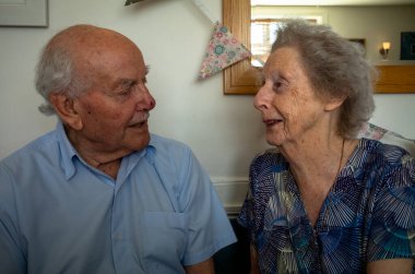 Yaşlı bir çift, her ikisi de 90 'larında, 70 yıllık evlilikten sonra birbirlerine sevgi ve sevgiyle bakıyorlar..