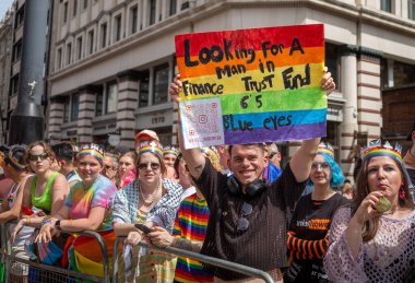 Londra / İngiltere - 29 Haziran 2024: Eşcinsel bir adam Londra 'daki yıllık Onur Yürüyüşü' nde yeni bir erkek arkadaş ararken elinde gökkuşağı pankartı tutuyor. Kutlama, LGBTQ + topluluklarından insanları bir araya getiriyor.