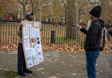 An evangelical Christian at Speaker's Corner in Hyde Park, London, is filmed as he talks by a man with a beard. clipart