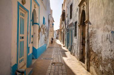 Genç bir adam Kairouan, Tunus 'un antik Medine' sinde dar bir geçitte yürüyor. Şehir, UNESCO 'nun dünya mirası ve İslam' ın dördüncü kutsal yeri..