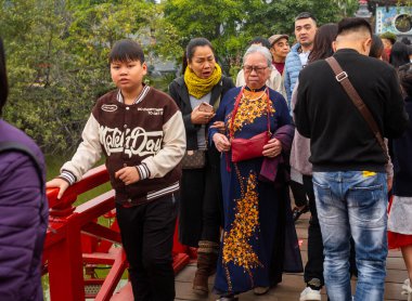 Geleneksel renkli ve yaşlı Vietnamlı bir kadın orta yaşlı kızı Toi Ngoc Son Temple ile Tet 'te ya da Ay Yeni Yılı, Hanoi, Vietnam' da yürüyor.