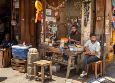 Erkekler, Stone Town Market, Zanzibar, Tanzanya 'daki bir anahtarcı dükkanında oturuyor