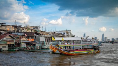 Turistler, Bangkok, Tayland 'daki Wat Arun' un karşısındaki Chao Phraya Nehri 'nden geleneksel olarak süslenmiş uzun kuyruklu bir tekneye biniyorlar..