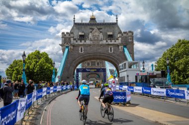 RideLondon 2022 'ye katılan iki erkek bisikletçi Londra' daki Tower Bridge 'deki bitiş çizgisine yaklaşıyor..