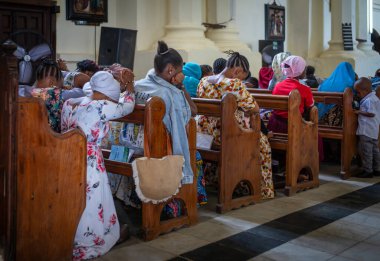 Renkli elbiseli kadınlar Pazar ayinlerinde Stone Town, Zanzibar, Tanzanya 'daki Anglikan İsa Kilisesi Katedrali' nde dua ediyorlar..