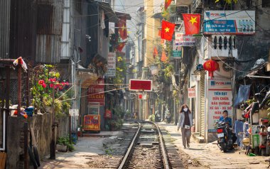 Yüz maskesi takan Vietnamlı bir kadın Hanoi, Vietnam 'daki Kham Thien Caddesi' ndeki yerleşim alanlarından geçen ana kuzey-güney demiryolu hattı boyunca yürüyor..
