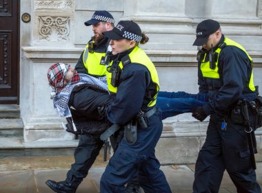 Londra / İngiltere - 9 Aralık 2023: İsrail 'in Gazze' deki saldırılarına karşı düzenlenen gösteride yüzünü kapatmayı reddettiği için tutuklanan Filistinli bir protestocu, polis tarafından kaçırıldı.