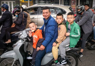 Vietnamlı bir adam ve üç genç çocuk, Hanoi, Vietnam 'da kasksız motosiklete biniyorlar..