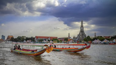 Geleneksel turist gezileri için uzun tekneler Chao Phraya Nehri 'nden geçerek Wat Arun ya da Tayland' ın Bangkok kentindeki Şafak Tapınağı 'na gider..
