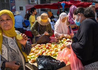 Kadınlar, Sousse, Tunus 'ta haftalık bir pazar olan Sunday Souk' taki bir meyve tezgahından elma satın alıyorlar.