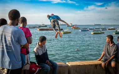 Gençler deniz duvarından atlayıp suya atlıyorlar. Stone Town, Zanzibar, Tanzanya 'da sular yükselince.