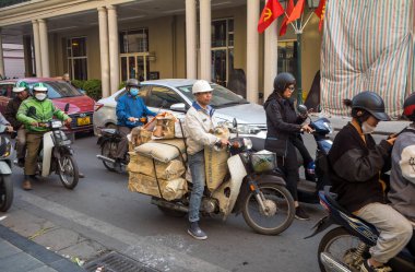 Vietnamlı bir adam, orta Hanoi Vietnam 'ında, Trang Tien' de aşırı miktarda çimento ve tuğla dolu bir motosikletin üzerinde oturuyor..