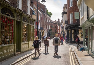 İnsanlar İngiltere 'nin Kuzey Yorkshire kentindeki tarihi York şehrindeki High Petergate mağazalarının önünden geçiyor. Şehir popüler bir turizm merkezidir..