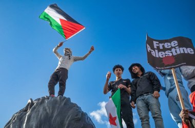 Londra, İngiltere. 14 Ekim 2023: Filistin yanlısı protestocular, Filistin 'e destek vermek ve İsrail' in Gazze 'ye saldırısına karşı elinde Filistin bayrağı bulunan dev bir aslan heykelinin üzerinde durdular..