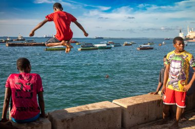Gençler deniz duvarından atlayıp suya atlıyorlar. Stone Town, Zanzibar, Tanzanya 'da sular yükselince.