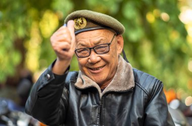 Vietnam 'da, Hanoi' de zeytin yeşili, asker tarzı bereli ve deri ceketli yaşlı bir Vietnamlı başparmağını kaldırıyor..