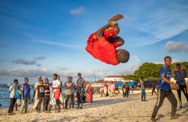 Genç bir adam öğleden sonra Tanzanya 'nın Zanzibar kentindeki Stone Town plajında akrobasi yapıyor..