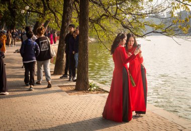 Vietnam, Hanoi 'de, Hoan Kiem Gölü' nün yanında selfie çekmek için iki Vietnamlı kadın duruyor..