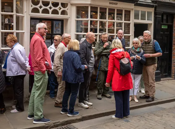 stock image A group of elderly tourists stand outside a shop in the Shambles, the famous ancient street in the heart of the city of York, North Yorkshire, UK