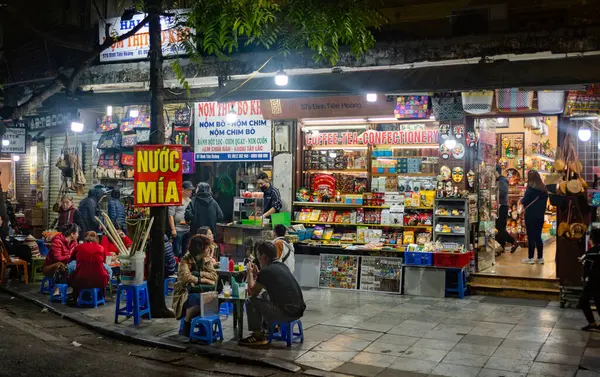 stock image Vietnamese people sit at a pavement cafe at nighttime to drink sugarcane juice in central Hanoi, Vietnam.