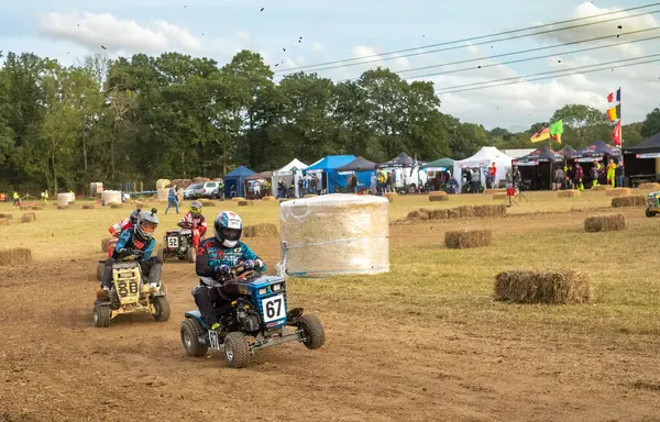 stock image Racing lawn mower drivers speed around a corner in the BLMRA 500, a Le Mans style 500 mile overnight lawn mower race in a field in West Sussex, UK.