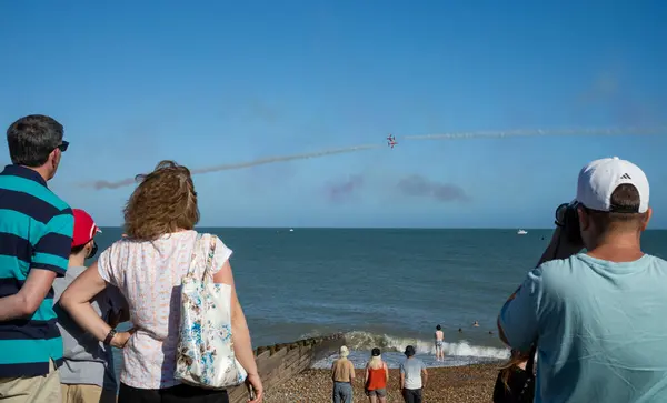 stock image People watch a deliberate near miss from Eastbourne beach as the world famous RAF display team The Red Arrows fly perform off the seafront at the annual Eastbourne Airbourne, an international airshow