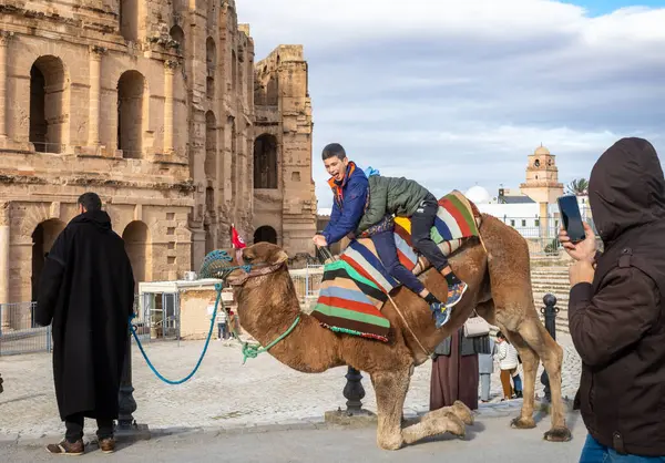 stock image Two young boys have a camel ride outside well-preserved Roman El Jem Amphitheatre (Thysdrus), Tunisia.