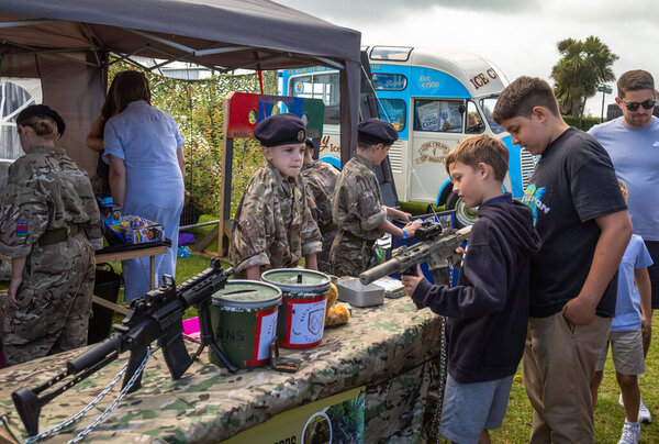 Young Army Cadets in military uniform show other children weapons  at a display stand in the military exhibition alongside the annual Eastbourne Airbourne, an international airshow