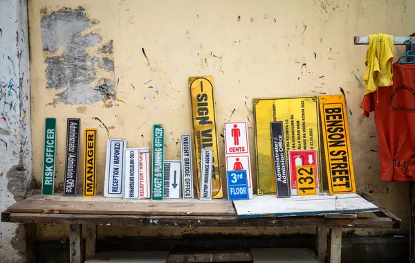 stock image A signmaker shows examples of his signs for sale on a wooden table in the street in central Dar es Salaam, Tanzania.