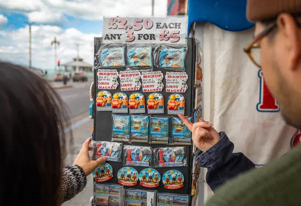 stock image Tourists stop to buy colourful fridge magnets showing traditional British seaside views of Brighton in East Sussex, UK