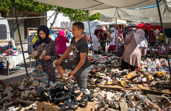 Pazar günü Sousse, Tunus 'ta haftalık pazarda kadın ayakkabısı satan genç bir adam..