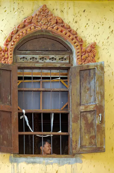 stock image A novice monk smiles at a window within the Saravoan Techo Pagoda in Phnom Penh, Cambodia.