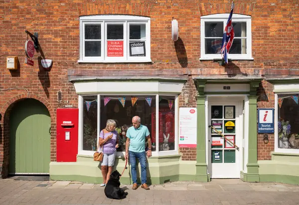 stock image A middle-aged couple with their labroador dog outside the post office in Steyning, West Sussex, UK.