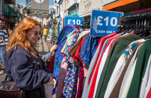 Женщина просматривает подержанную и винтажную одежду для продажи за 10 наличных только в The Lanes в Брайтоне, Ист-Сассекс, Великобритания 