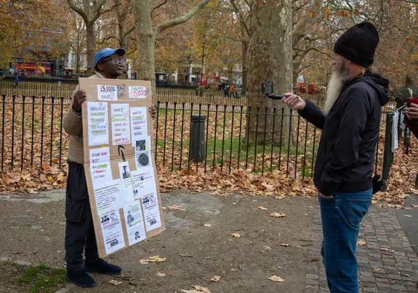 stock image An evangelical Christian at Speaker's Corner in Hyde Park, London, is filmed as he talks by a man with a beard.